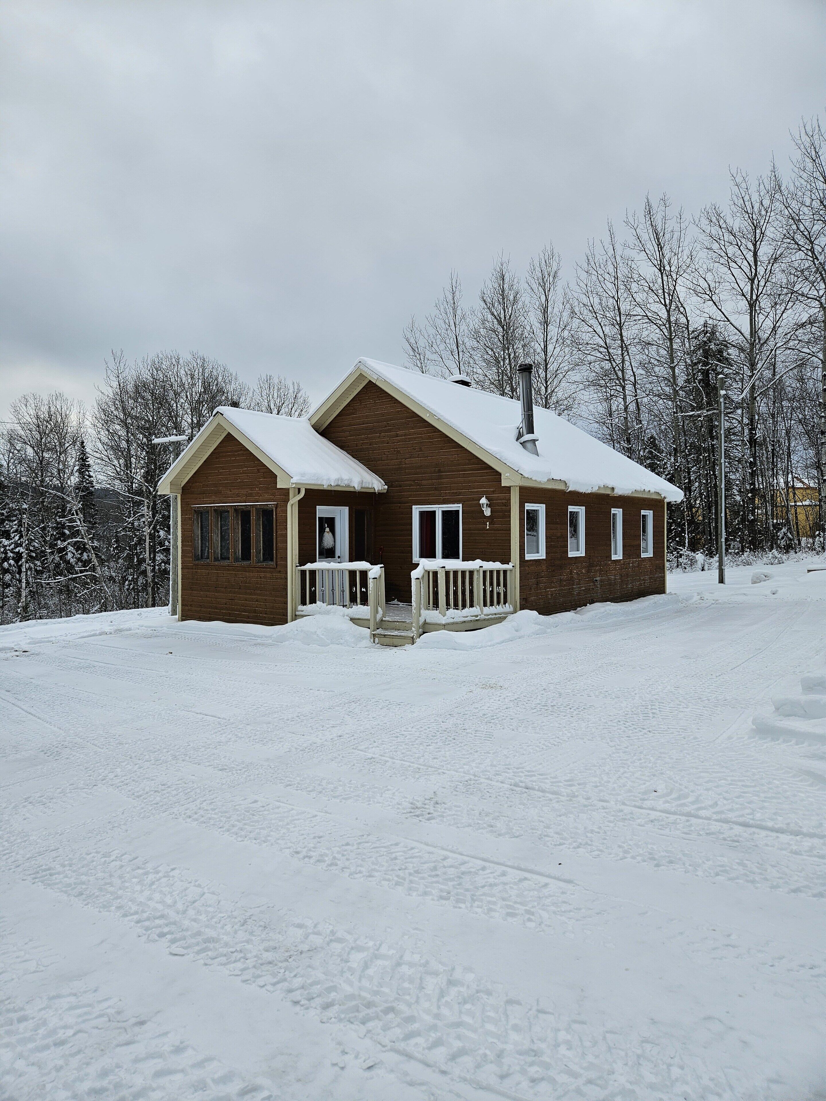 A wooden cabin with a snow-covered roof and a porch.