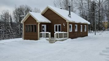 A wooden cabin with a snow-covered roof and a porch.