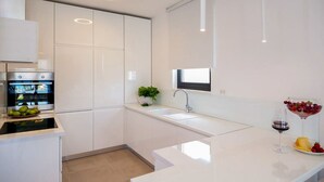 A modern kitchen with white cabinetry, a built-in oven, a sink, and a countertop with a potted plant and fruit. - Villa Tetra - Six Bedroom Villa, Sleeps 11 (Okrug Gornji)