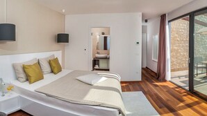 A modern bedroom with a large bed, bedside tables, a built-in sink, and a sliding glass door to a balcony. - Villa Tetra - Six Bedroom Villa, Sleeps 11 (Okrug Gornji)