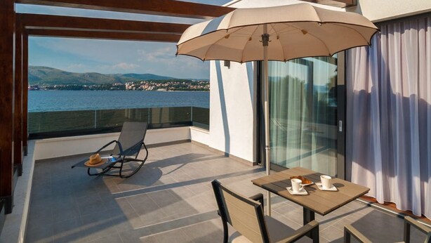 A balcony with a table and chairs, a large umbrella, and a view of the sea and hills. - Villa Panda - Six Bedroom Villa, Sleeps 11 (Okrug Gornji)