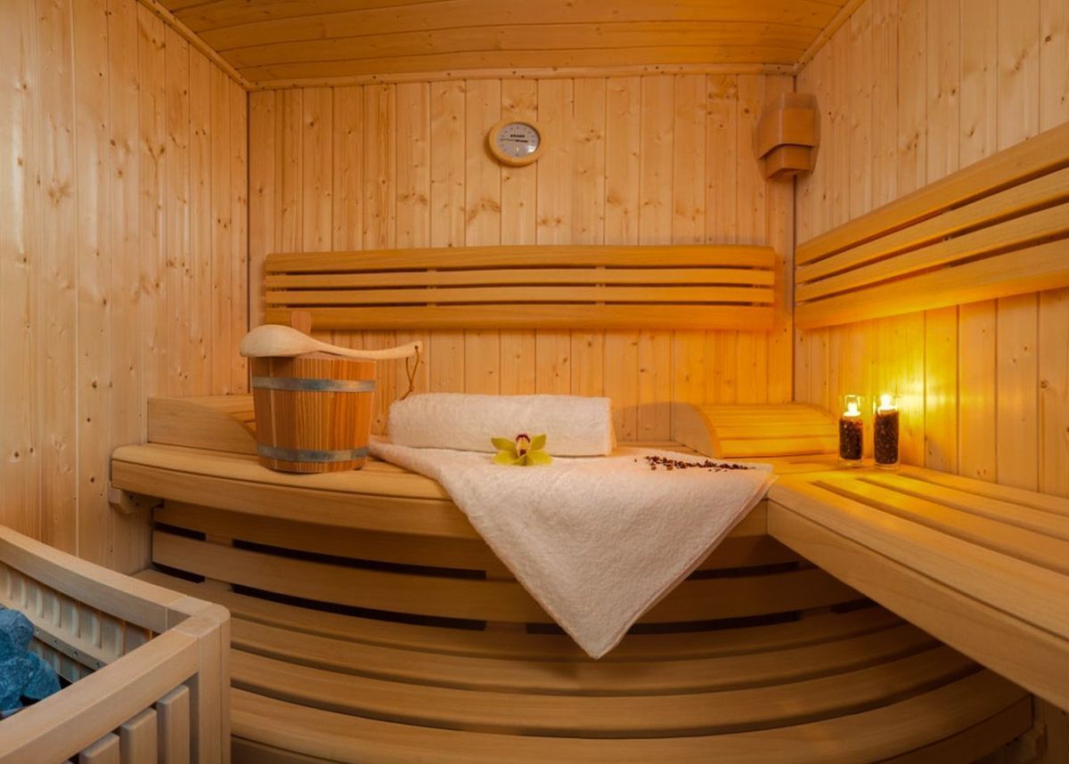 En sauna med træbænke, et håndklæde, en træspand og to flasker olie.