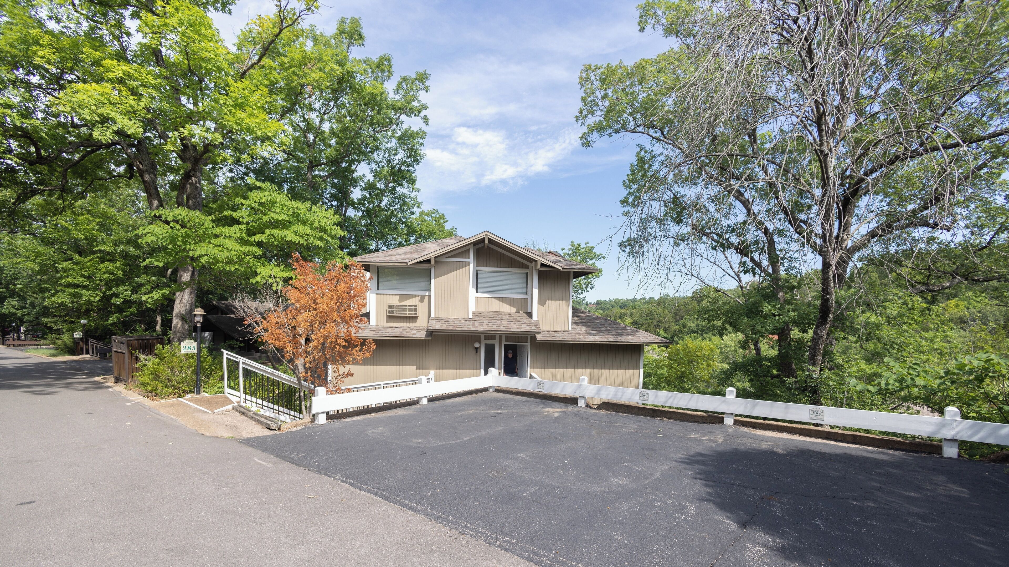 A two-story house with a garage, surrounded by trees and a white fence.