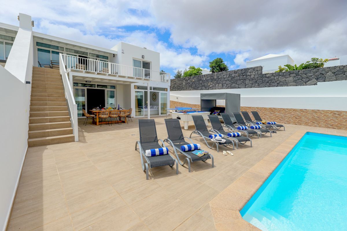 A modern resort with a swimming pool, sun loungers, and a dining area.