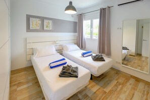 Une chambre d’hôtel avec deux lits simples, un grand miroir et une fenêtre avec des rideaux.