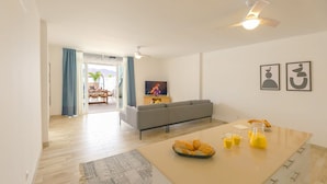 Een moderne woonkamer met een bank, een eettafel met ontbijtproducten en een televisie.