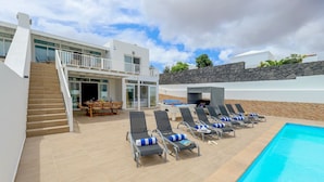 Een modern resort met een zwembad, ligbedden en een eetgedeelte.