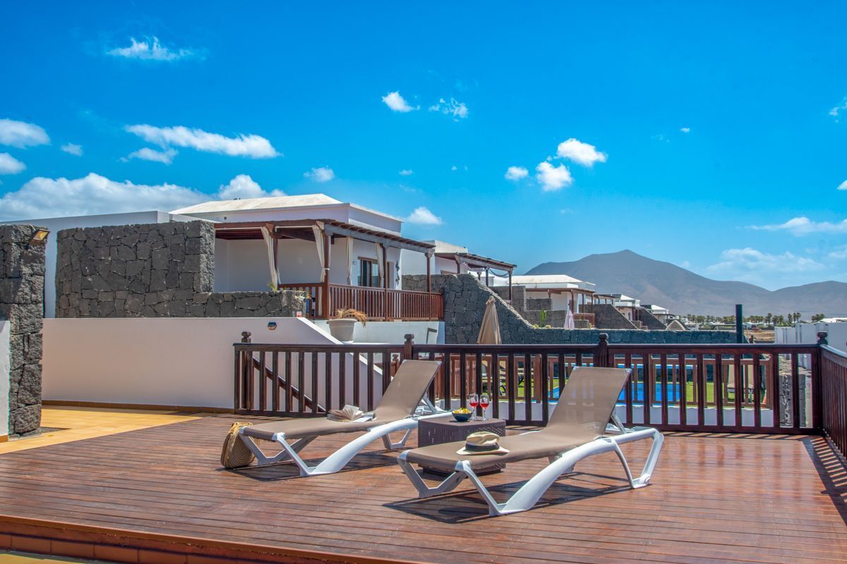 A wooden deck with two sun loungers and a stone wall.