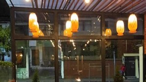 An outdoor seating area with tables and chairs, a fire pit, and hanging lights.