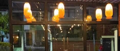 An outdoor seating area with tables and chairs, a fire pit, and hanging lights.