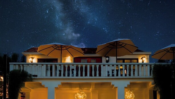 A two-story building with a balcony, under a starry night sky.
