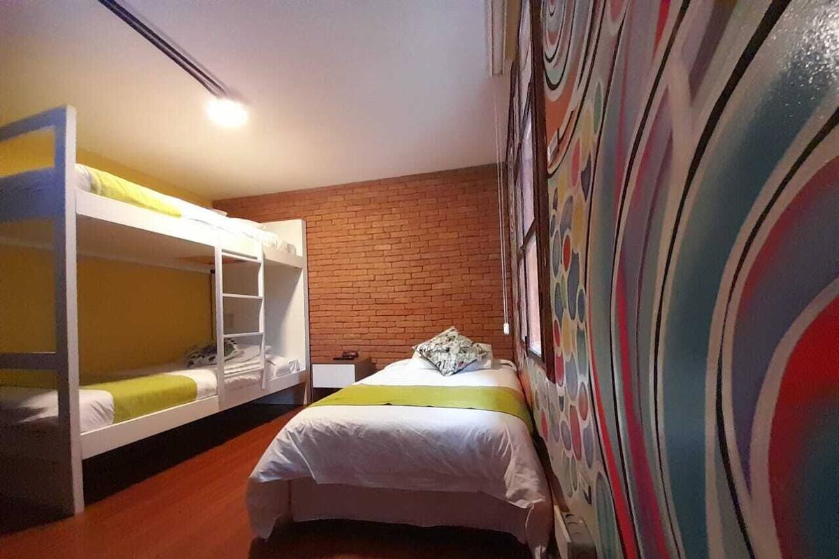 A room with bunk beds, a brick wall, and a colorful abstract mural.