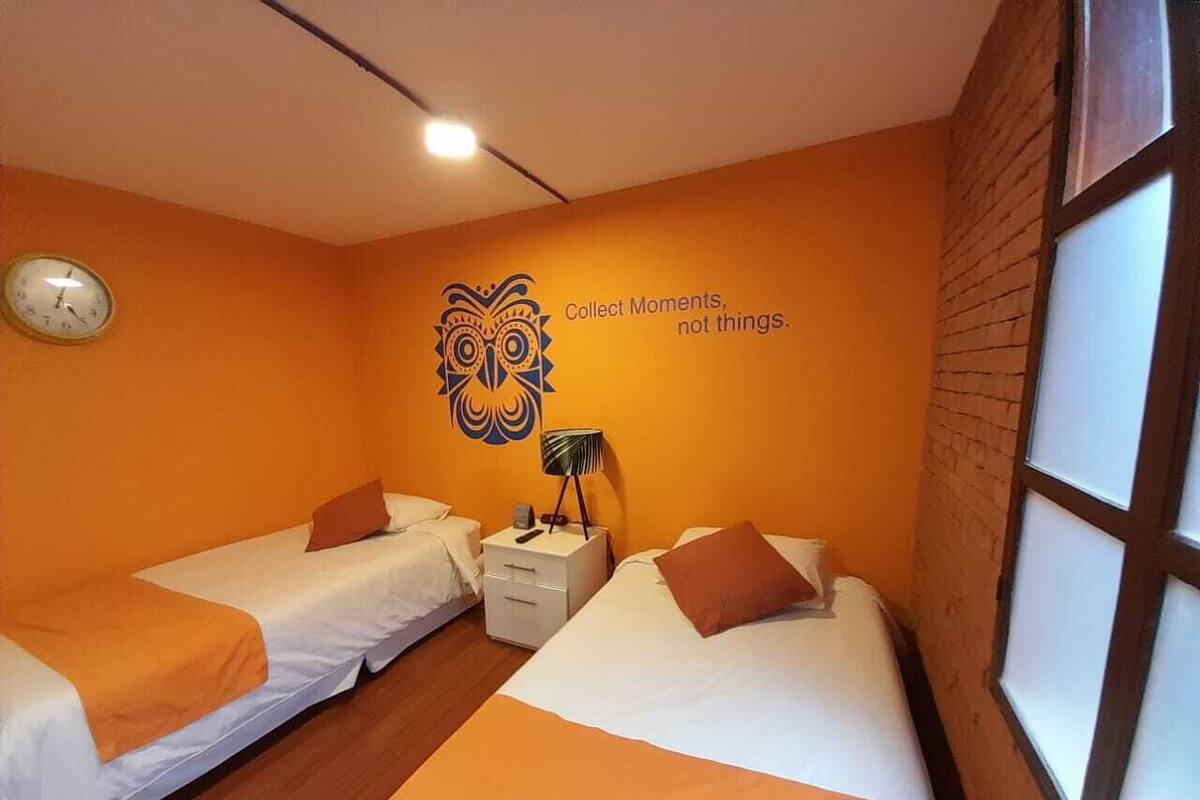 A room with two beds, a clock on the wall, and a motivational quote.