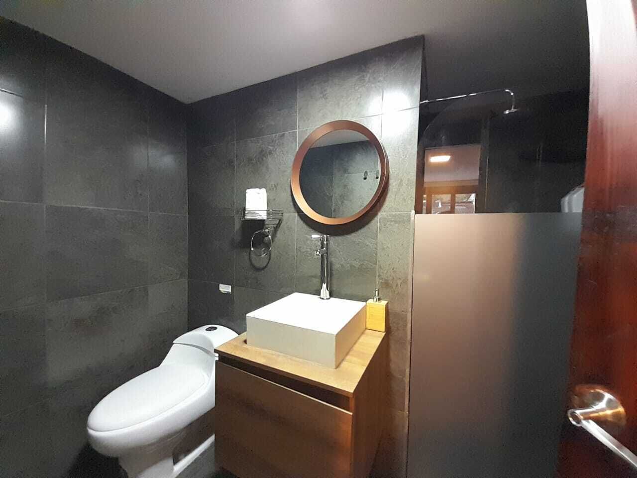 Un bagno moderno con un WC bianco, un mobile bagno in legno con specchio e un porta asciugamani a parete.
