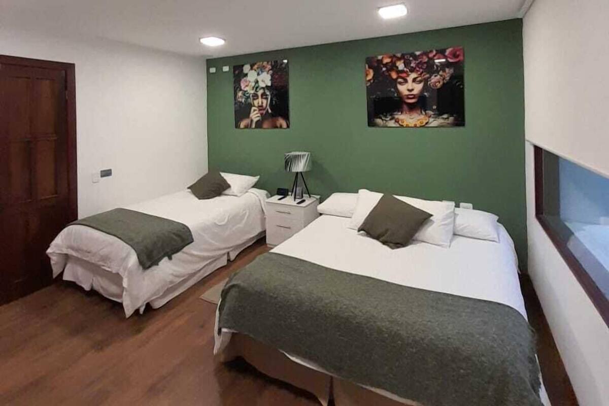 A hotel room with two beds, green walls, and artwork on the wall.