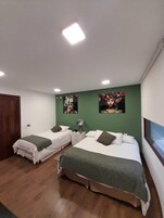 Habitación de hotel con dos camas, paredes verdes y una obra de arte en la pared.