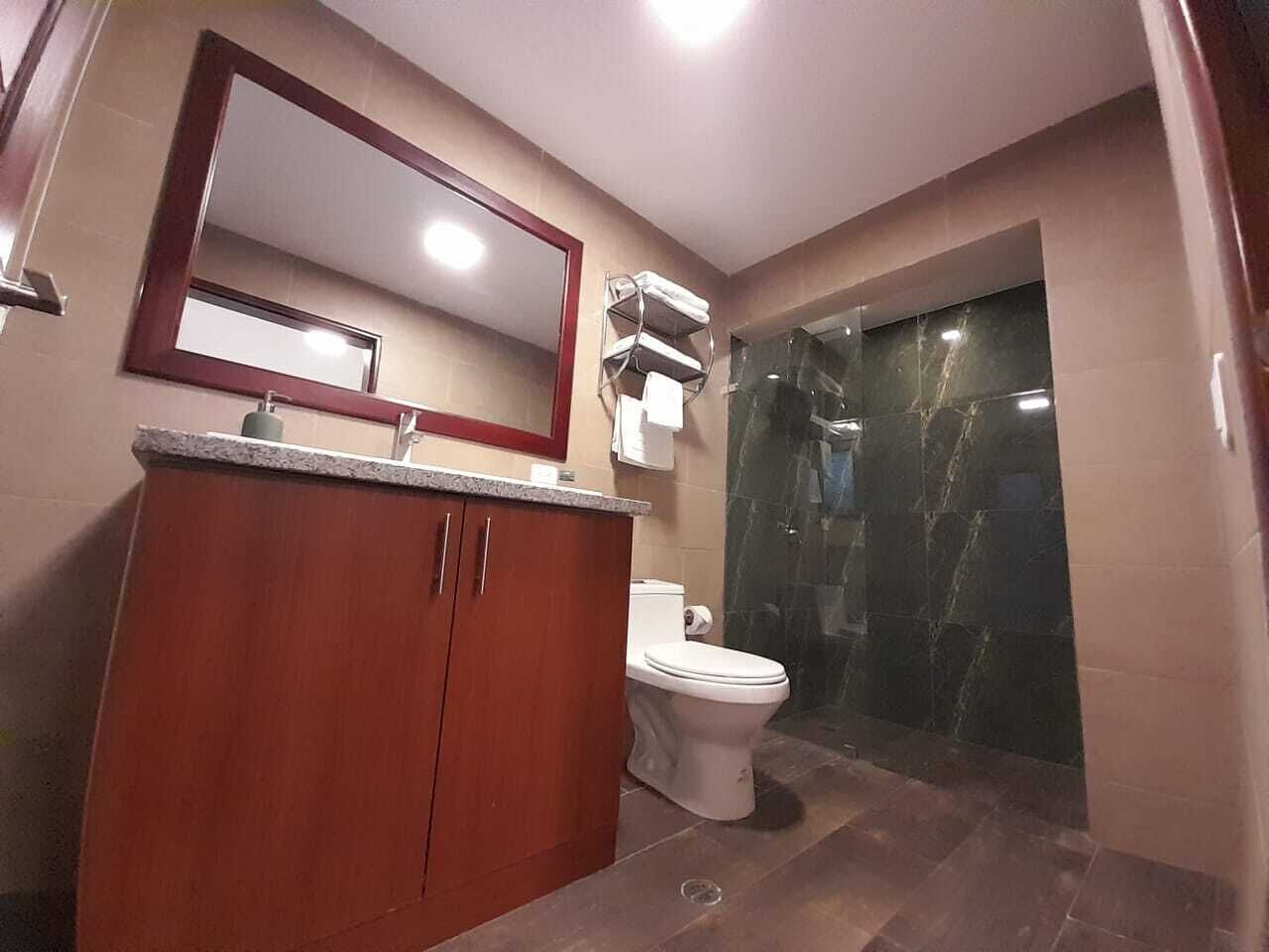 A bathroom with a wooden vanity, a white toilet, and a glass-enclosed shower.