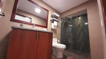 A bathroom with a wooden vanity, a white toilet, and a glass-enclosed shower.