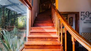 A wooden staircase with a handrail, leading to a landing with a sign that reads "59% HOST BOUTIQUE".