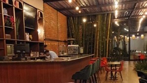 A restaurant with a bar area, seating, and a central fire feature.