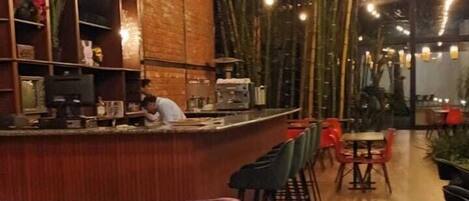 A restaurant with a bar area, seating, and a central fire feature.