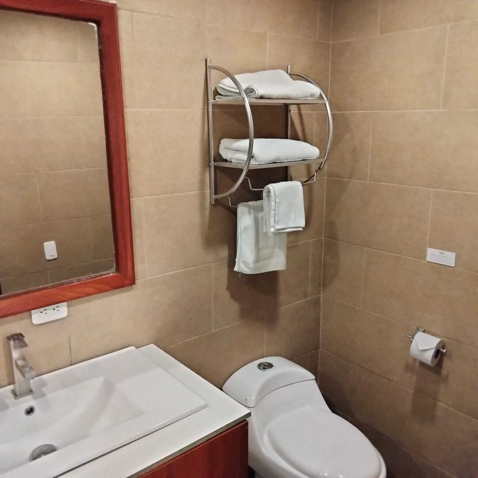 Ein Badezimmer mit Waschbecken, Toilette und einem Handtuchhalter mit mehreren Handtüchern.