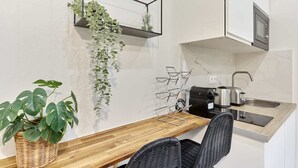 A compact kitchen with a wooden countertop, a sink, a kettle, and a toaster. There are two chairs and a potted plant. - Charon 4 - Studio Apartment, Sleeps 2 (Paris)