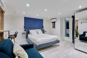 Une chambre moderne avec un lit, un bureau et une chaise. Une porte-fenêtre coulissante donne accès à un balcon.