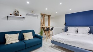 Une chambre moderne avec un canapé bleu, un lit avec une literie blanche et une petite table avec des chaises.