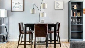 Ein Essbereich mit Tisch und vier Stühlen, zwei Wandlampen sowie zwei gerahmten Motivationssprüchen.