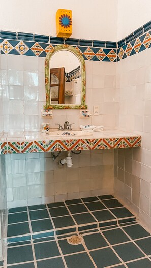 Un baño con piso de azulejos, un lavamanos con espejo y un inodoro.