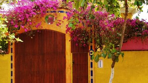 A yellow building with a wooden door and a small window. - Standard 1 bedroom suite  #7
 (San Patricio)