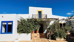 A white building with a blue door and window, a balcony with a yellow door, and potted plants. - Can Pep Tauet Formentera, al Centro de la Isla, muy Bien Comunicada (FORMENTERA)
