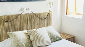 A bedroom with a bed, pillows, a painting, a window, and a nightstand. - Can Pep Tauet Formentera, al Centro de la Isla, muy Bien Comunicada (FORMENTERA)