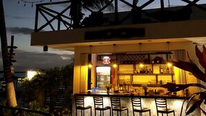 An outdoor bar area with a counter and bar stools, a palm tree, and string lights. - Hotel Aldea 19 Bacalar (Bacalar)