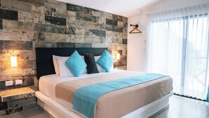 A modern hotel room with a large bed, a wooden accent wall, and a view of the outdoors. - Hotel Aldea 19 Bacalar (Bacalar)