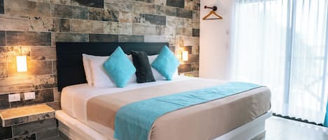 A modern hotel room with a large bed, a wooden accent wall, and a view of the outdoors.