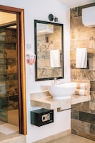 Un baño con un lavamanos blanco, un espejo y un perchero para toallas.