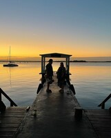 Un muelle se adentra en aguas tranquilas, con un barco pequeño y una estructura cubierta al final.