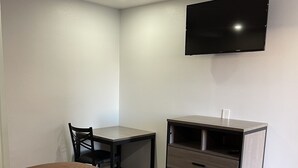 A hotel room with a bed, a desk, a chair, a TV mounted on the wall, and a wardrobe. - Welcome Inn & Suites (Anaheim)