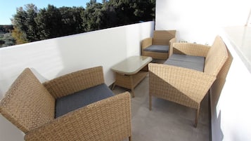 Un balcon agrémenté de meubles en osier, notamment deux chaises et une petite table.