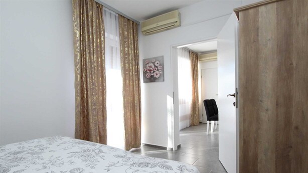 Quarto de hotel com cama, guarda-roupa, cadeira e porta que dá para outro espaço.