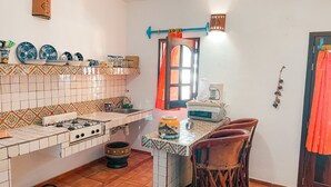 Eine Küche mit Gaskochfeld, Spüle und einem Fenster mit Vorhang.