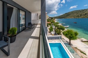 Ein Balkon mit Pool, Sitzgelegenheiten im Freien und Blick aufs Meer.
