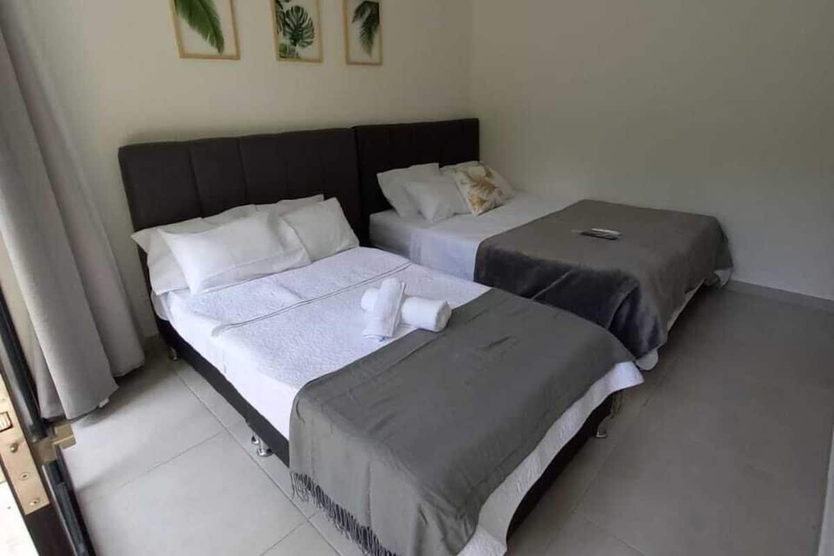 Quarto de hotel com duas camas, uma janela grande e vista para o exterior.