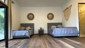 Een moderne slaapkamer met twee bedden, houten vloeren en ronde decoratie aan de muur.