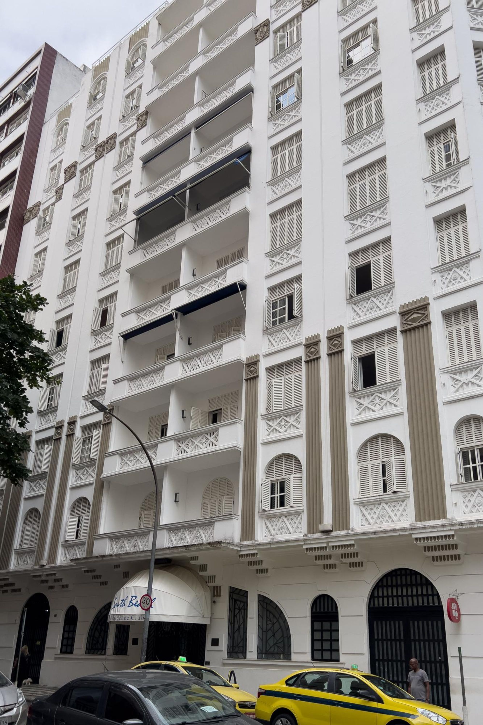 Un hotel de varios pisos con balcones, una entrada principal y un cartel que indica que es un hotel.