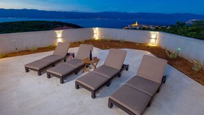 A rooftop terrace with six lounge chairs and a small table, overlooking a coastal cityscape at dusk. - Villa Giulietta with a heated pool, fitness & Seaview (Vrbnik (Krk))
