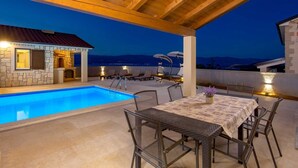 An outdoor pool area with a stone building, lounge chairs, and a table with a vase of flowers. - Villa Giulietta with a heated pool, fitness & Seaview (Vrbnik (Krk))