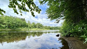 A calm river with a clear reflection of the sky and surrounding greenery. - Dome #4 –Nestled in nature (Saint-Gabriel-de-Valcartier)